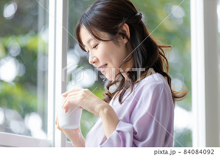 マグカップを持って窓辺に立つ女性 マグカップを持って窓辺に立つ女性 84084092