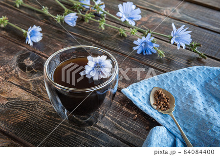 Chicory drink in thermo glass cup with fresh flowers on wooden table Chicory drink in thermo glass cup with fresh flowers on wooden table 84084400