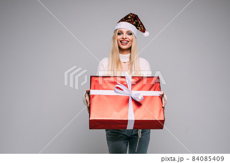 Pretty young woman is holding Christmas gift Pretty young woman is holding Christmas gift 84085409