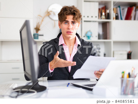 Upset attractive young businessman working documents and laptop Upset attractive young businessman working documents and laptop 84085581