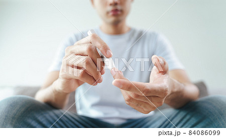 Asian man using lancet on finger for checking blood sugar level by Glucose meter, Healthcare and Medical, diabetes, glycemia concept 84086099