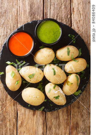 Papas arrugadas wrinkly potatoes is the signature dish of the Canary Islands close up in the plate. Vertical top view Papas arrugadas wrinkly potatoes is the signature dish of the Canary Islands close up in the plate. Vertical top view 84086409