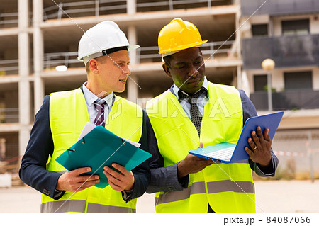 Head of construction and representative of developer are discussing documents and drawings at construction site Head of construction and representative of developer are discussing documents and drawings at construction site 84087066