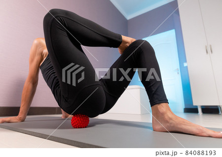 Close-up young caucasian woman doing myofascial self-massage of her thigh and buttocks with a massage ball on a massage mat. 4k resolution Close-up young caucasian woman doing myofascial self-massage of her thigh and buttocks with a massage ball on a massage mat. 4k resolution 84088193
