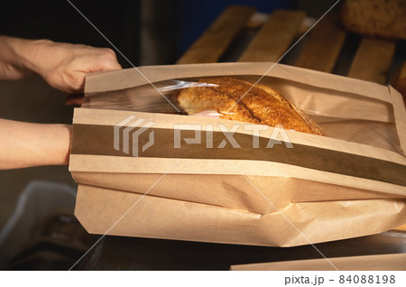 a loaf of white artisan hot bread in a paper bag with transparent inserts on a white background. Healthy food. Homemade natural products a loaf of white artisan hot bread in a paper bag with transparent inserts on a white background. Healthy food. Homemade natural products 84088198