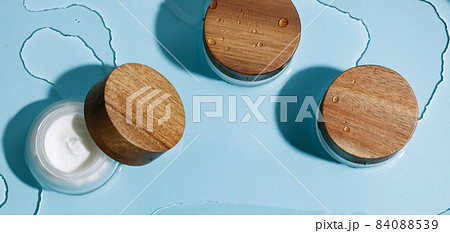 Moisture face cream in glass jar with wood lid on ocean blue wet background. Beauty, spa, wellness zero waste concept 84088539