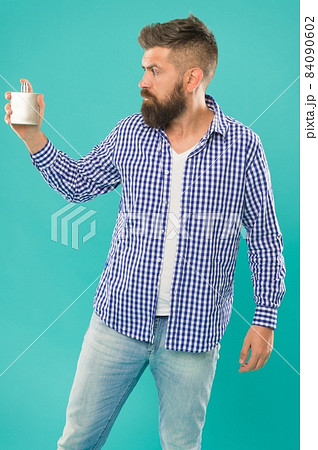 trendy caucasian guy with beard and mustache presenting male perfume on blue background, smell trendy caucasian guy with beard and mustache presenting male perfume on blue background, smell 84090602