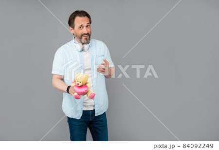 Happy senior man hold teddy bear with heart grey background copy space, valentines day Happy senior man hold teddy bear with heart grey background copy space, valentines day 84092249