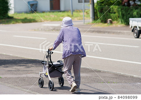 晴れた日に手押し車を押して散歩する高齢者の女性 晴れた日に手押し車を押して散歩する高齢者の女性 84098099