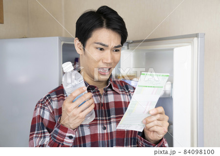 冷蔵庫を開けたまま健康診断の結果を見て悩む男性 冷蔵庫を開けたまま健康診断の結果を見て悩む男性 84098100