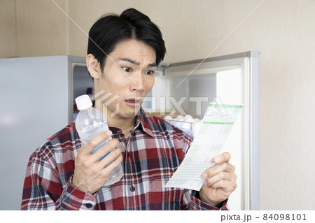 冷蔵庫を開けたまま健康診断の結果を見て悩む男性 冷蔵庫を開けたまま健康診断の結果を見て悩む男性 84098101
