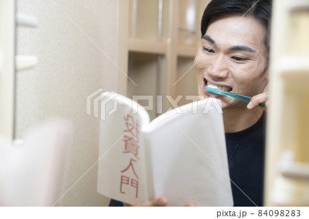 洗面所で歯磨きをしながら本を読む男性 洗面所で歯磨きをしながら本を読む男性 84098283