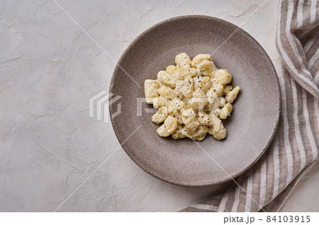 Homemade gnocchi, prepared with potato and whole grain flour dough with cream sauce on gray concrete Homemade gnocchi, prepared with potato and whole grain flour dough with cream sauce on gray concrete 84103915