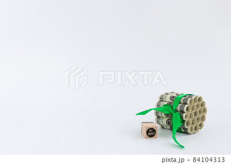 100 dollars tied with green ribbon and wooden cube with words for you on it. 84104313