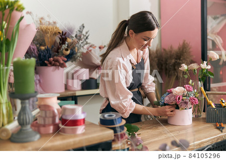 Professional florist young woman is doing bouquets at flower shop 84105296