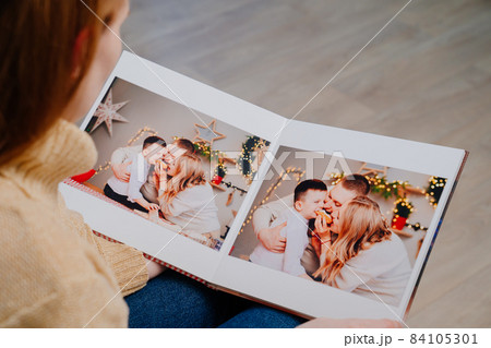 woman flips through the pages of photobook from a family photo shoot in kitchen 84105301