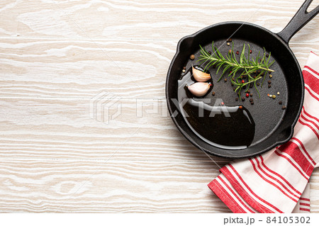 Cast iron frying pan with rosemary, garlic, pepper, oil copy space Cast iron frying pan with rosemary, garlic, pepper, oil copy space 84105302