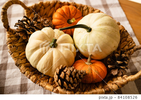 basket with small decorative white and orange pumpkins and cones. basket with small decorative white and orange pumpkins and cones. 84108526