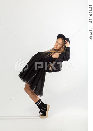 A full-length portrait of dancing young girl with long brown hair dressed in a hooligan style. A full-length portrait of dancing young girl with long brown hair dressed in a hooligan style. 84109885
