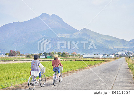 自転車で湯布院を散策する若い女性と友達 84111554