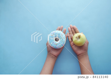 hand holding donuts and apple on hand on blue background  84113140