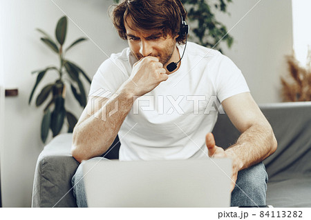 Young man businessman with headset working on laptop from home 84113282