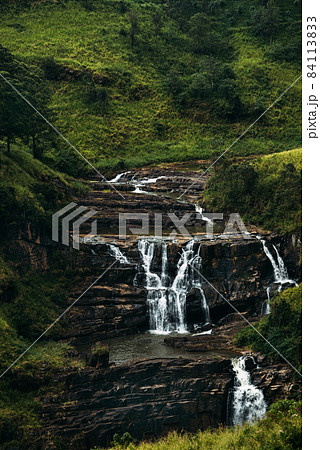 Waterfall among the green mountains. Waterfalls Of Sri Lanka. Landscapes Of Asia. Aerial photography. Tea plantation. Green hill. Mountain river. Small waterfall. Sri lanka Waterfall among the green mountains. Waterfalls Of Sri Lanka. Landscapes Of Asia. Aerial photography. Tea plantation. Green hill. Mountain river. Small waterfall. Sri lanka 84113833