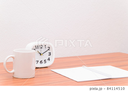The notebook and the clock are on the table. 84114510