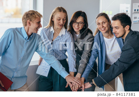Business team showing unity with their hands together Business team showing unity with their hands together 84117381