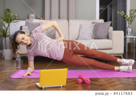 Beautiful sporty cheerful woman is doing side plank exercise 84117683