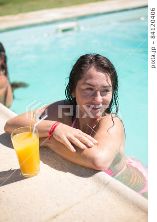 Charming young woman swimming in pool Charming young woman swimming in pool 84120406