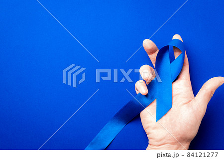 Prostate care. Awareness prostate cancer of men health in November. Blue ribbon in hands isolated on deep blue background. World cancer day and world diabetes day concept. Prostate care. Awareness prostate cancer of men health in November. Blue ribbon in hands isolated on deep blue background. World cancer day and world diabetes day concept. 84121277