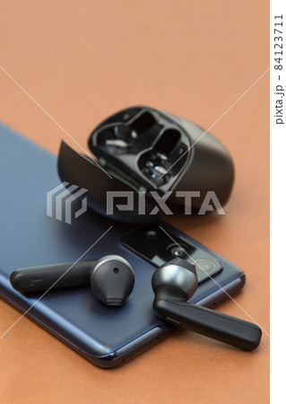 Wireless headphones are on the phone screen on a brown background, the concept of a new purchase 84123711