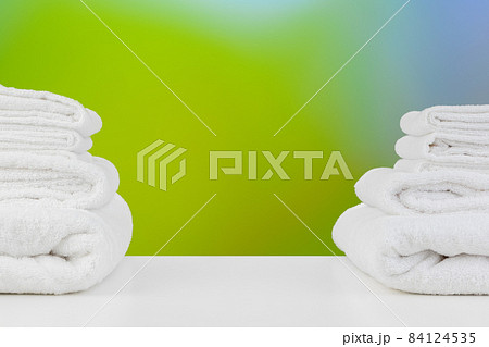 Stacked white spa towels on table against blurred background 84124535