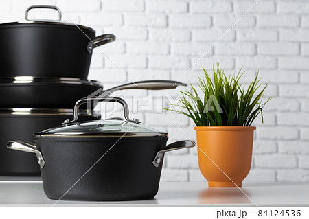 Black kitchenware on table against white brick wall 84124536
