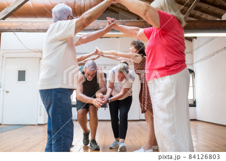 Funny senior dancers making arch with their arms for couple Funny senior dancers making arch with their arms for couple 84126803