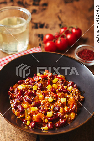 Chili Con Carne with ground beef, beans and corn in dark bowl on wooden background. Mexican and Texas cuisine Chili Con Carne with ground beef, beans and corn in dark bowl on wooden background. Mexican and Texas cuisine 84127456