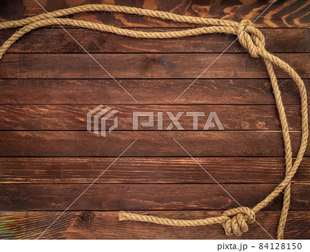 Wooden background made of dark brown boards with hemp ropes. Deck texture. Wooden background made of dark brown boards with hemp ropes. Deck texture. 84128150