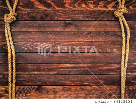 Wooden background made of dark brown boards with hemp ropes. Deck texture. 84128151