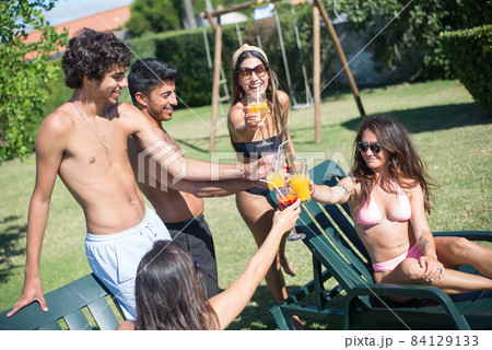 Happy friends partying at poolside Happy friends partying at poolside 84129133