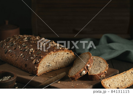 Sliced Homemade Whole Grain Bread with Seeds on a Cutting Board 84131115