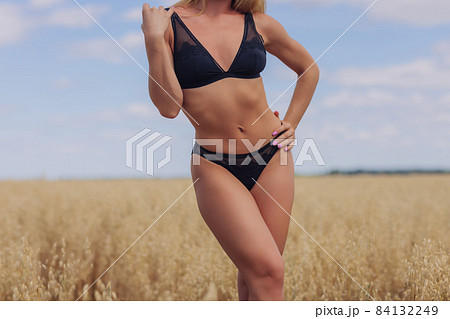 A young woman in underwear in a field of wheat. 84132249