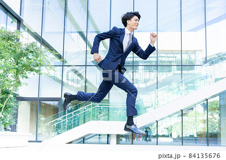 オフィスビルの前でジャンプするビジネスマン　撮影協力「LINK FOREST] 84135676