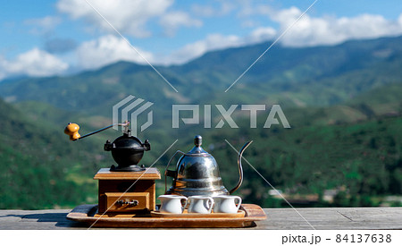 Manual coffee grinder for Kettle and coffee mugs grinding coffee beans. mountain background Manual coffee grinder for Kettle and coffee mugs grinding coffee beans. mountain background 84137638