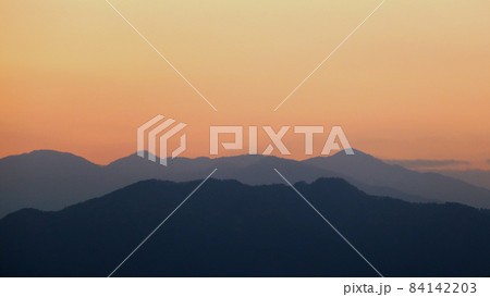 夕焼けに赤く染まる空と浮かび上がる幻想的な山のシルエット 夕焼けに赤く染まる空と浮かび上がる幻想的な山のシルエット 84142203