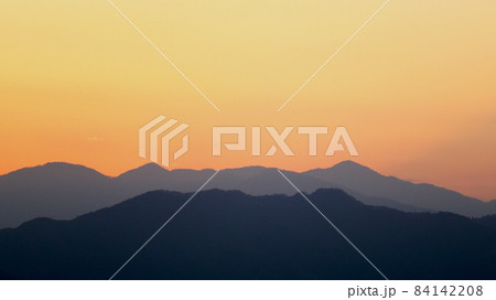 夕焼け色にうっすら染まる空と浮かび上がる山のシルエット 夕焼け色にうっすら染まる空と浮かび上がる山のシルエット 84142208