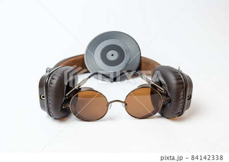 on-ear headphones with sunglasses and a vinyl record lie on a white background 84142338