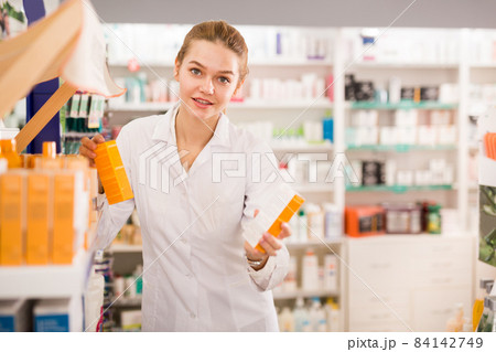 Positive woman pharmacist working in pharmaceutical shop Positive woman pharmacist working in pharmaceutical shop 84142749
