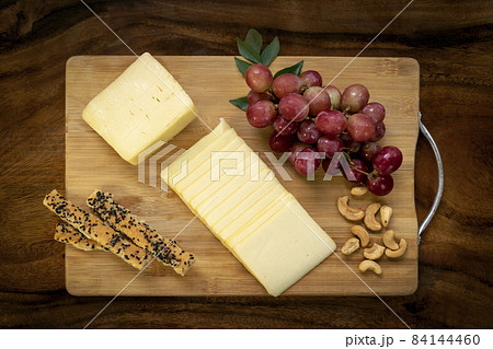 Sliced cheddar cheese block on wood board Sliced cheddar cheese block on wood board 84144460