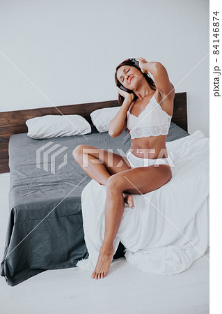 beautiful woman in lingerie listening to music in headphones on the bed in the bedroom beautiful woman in lingerie listening to music in headphones on the bed in the bedroom 84146874